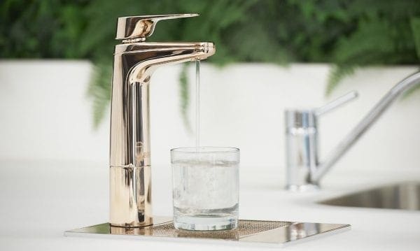 Billi XL Rose Gold dispenser on riser and font with glass of water