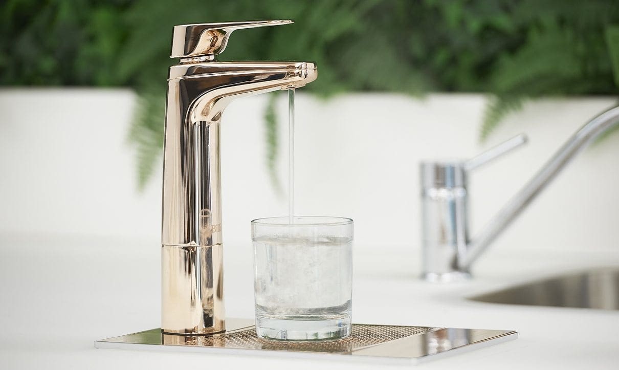 Rose Gold XL Dispenser on font with glass of water