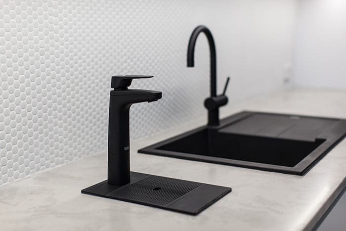 Matte Black XL dispenser on riser and font next to kitchen sink